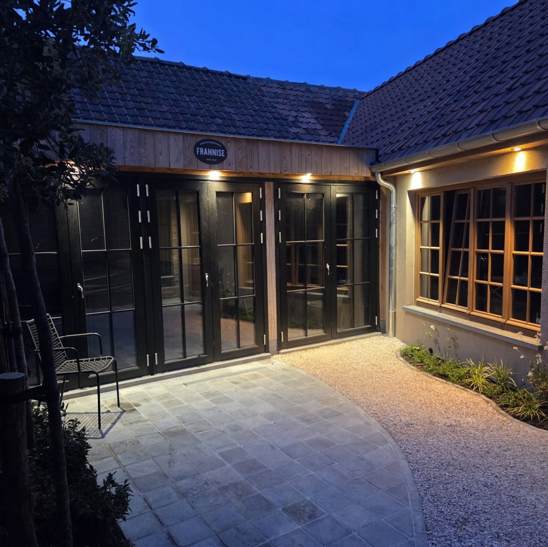 De verlichte ingang van vakantiewoning Frannise bij het vallen van de avond